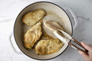 Searing chicken in a large skillet.