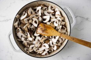 Adding fresh mushrooms to the skillet.
