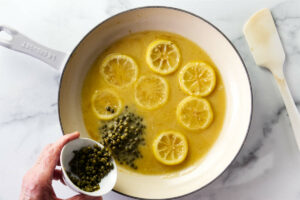 Adding capers to piccata sauce.