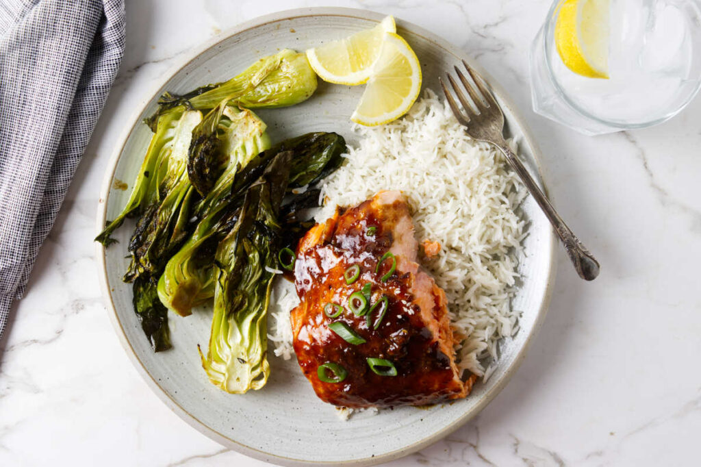 A serving of ginger garlic salmon on a bed of rice with bok choy.