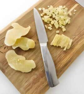 Chopping crystalized ginger on a cutting board.
