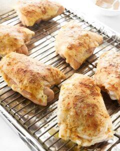 Placing chicken thigh on a rack over a baking sheet.