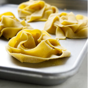Swirled piles of fresh einkorn pasta on a sheet pan.