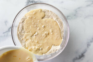 Pouring the wet mixture into the dry mixture to make waffles.