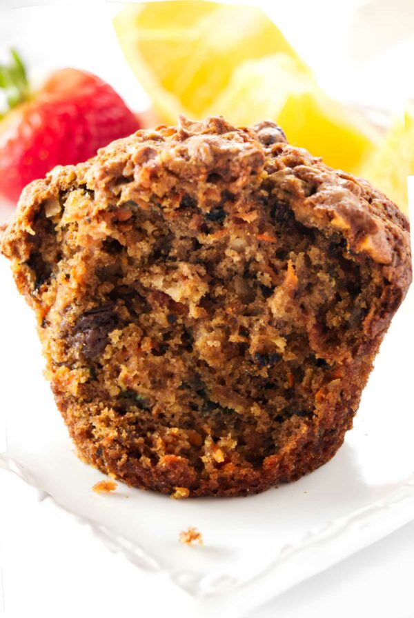 A partially eaten morning glory carrot apple muffin on a plate.