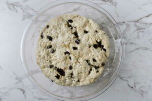 Proofing cinnamon raisin bread dough in a glass bowl.
