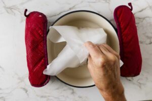 Using parchment as a sling to lower raisin bread dough into a hot dutch oven.