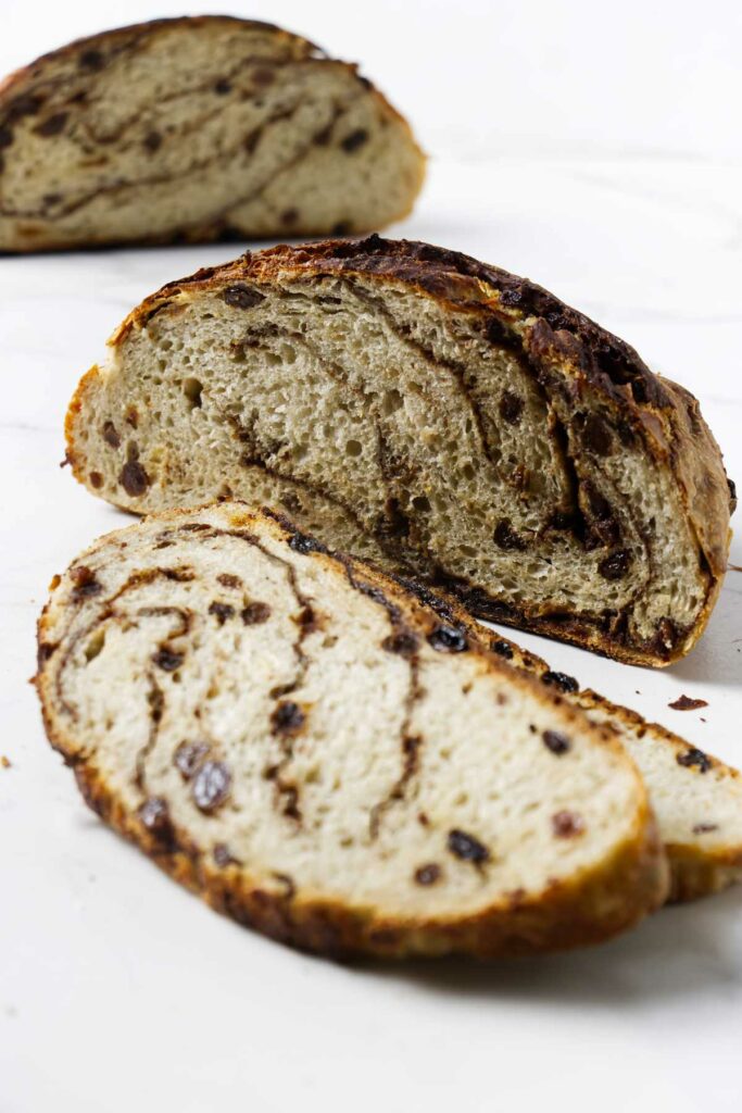 A partially sliced boule of no knead cinnamon raisin bread on a counter.
