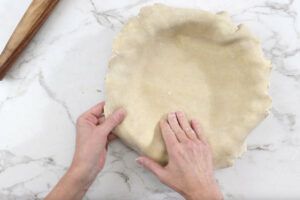 Pressing pie dough into a pie crust.