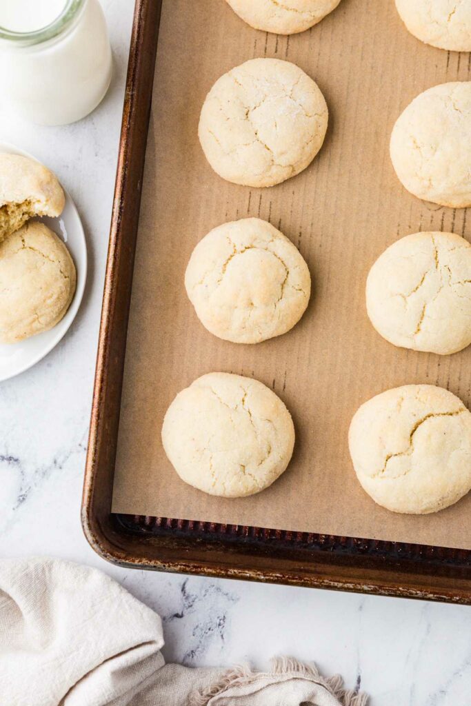 Several soft sourdough drop sugar cookies on a parchment lined cookie sheet.