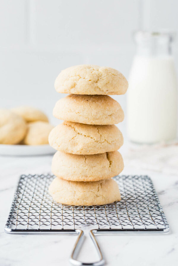 A stack of five sourdough discard sugar cookies in front of a jar of milk.