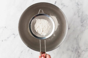 Sifting the dry ingredients into a mixing bowl.