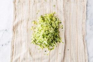 Shredded zucchini on a dish towel.