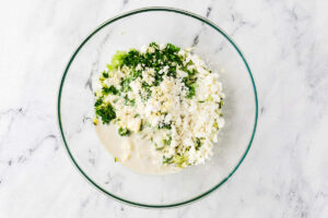 Adding the sourdough discard, herbs, and cheese to the bowl.