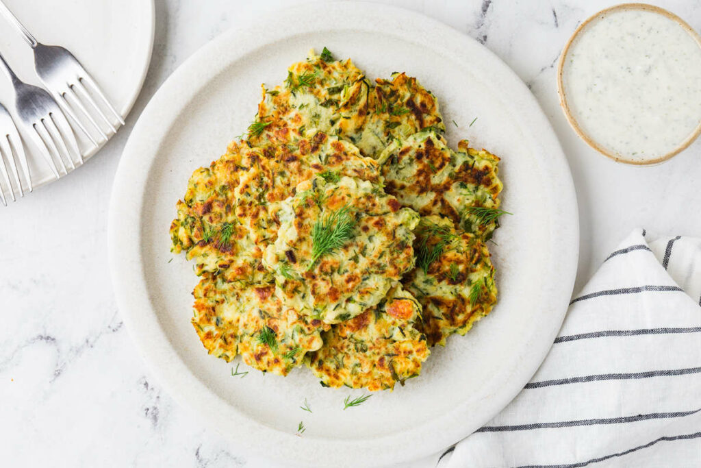 A platter filled with sourdough zucchini fritters next to ranch dressing.