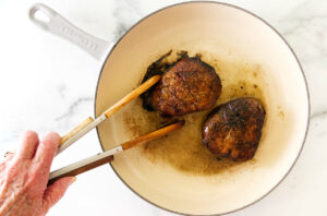 Searing two steaks in a skillet.