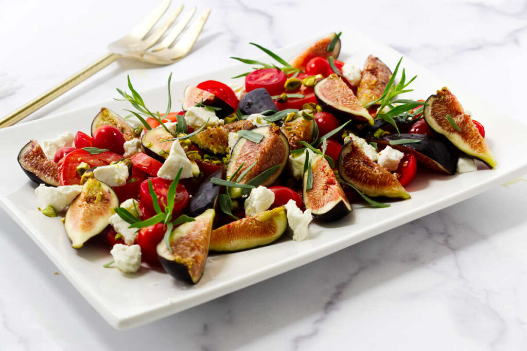 A tomato fig salad on a white plate.