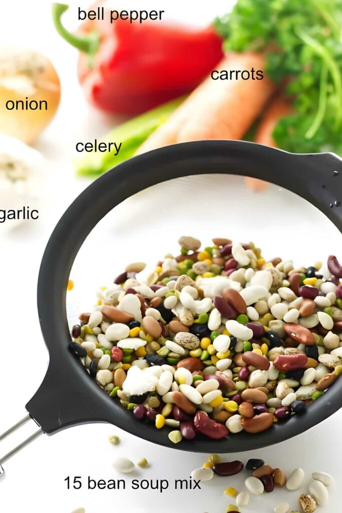 Strainer with colorful 15 bean soup mix and assorted labeled vegetables.