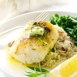 Baked white fish with herb butter on rice pilaf, greens, and lemon.
