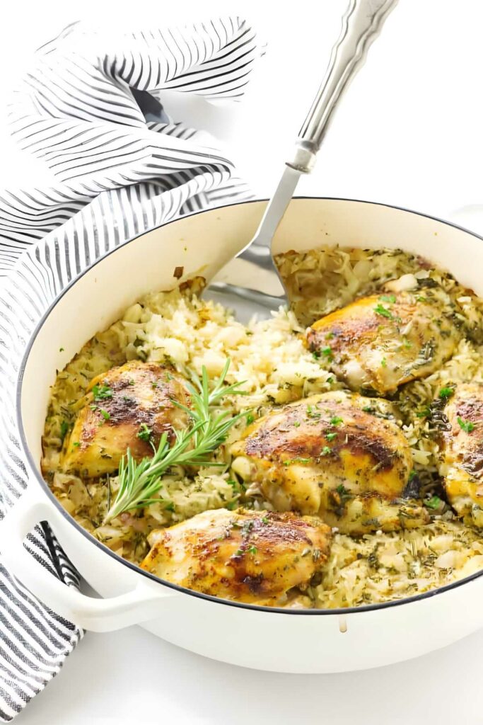 White pot of baked rice and chicken, herbs, and a serving spatula.