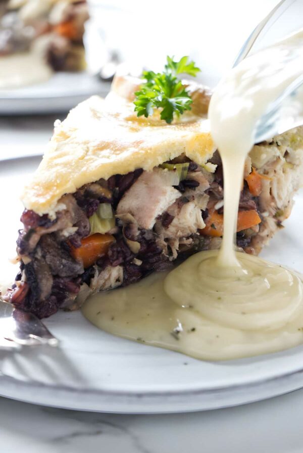 Chicken and rice pie slice topped with white gravy, garnished with parsley.