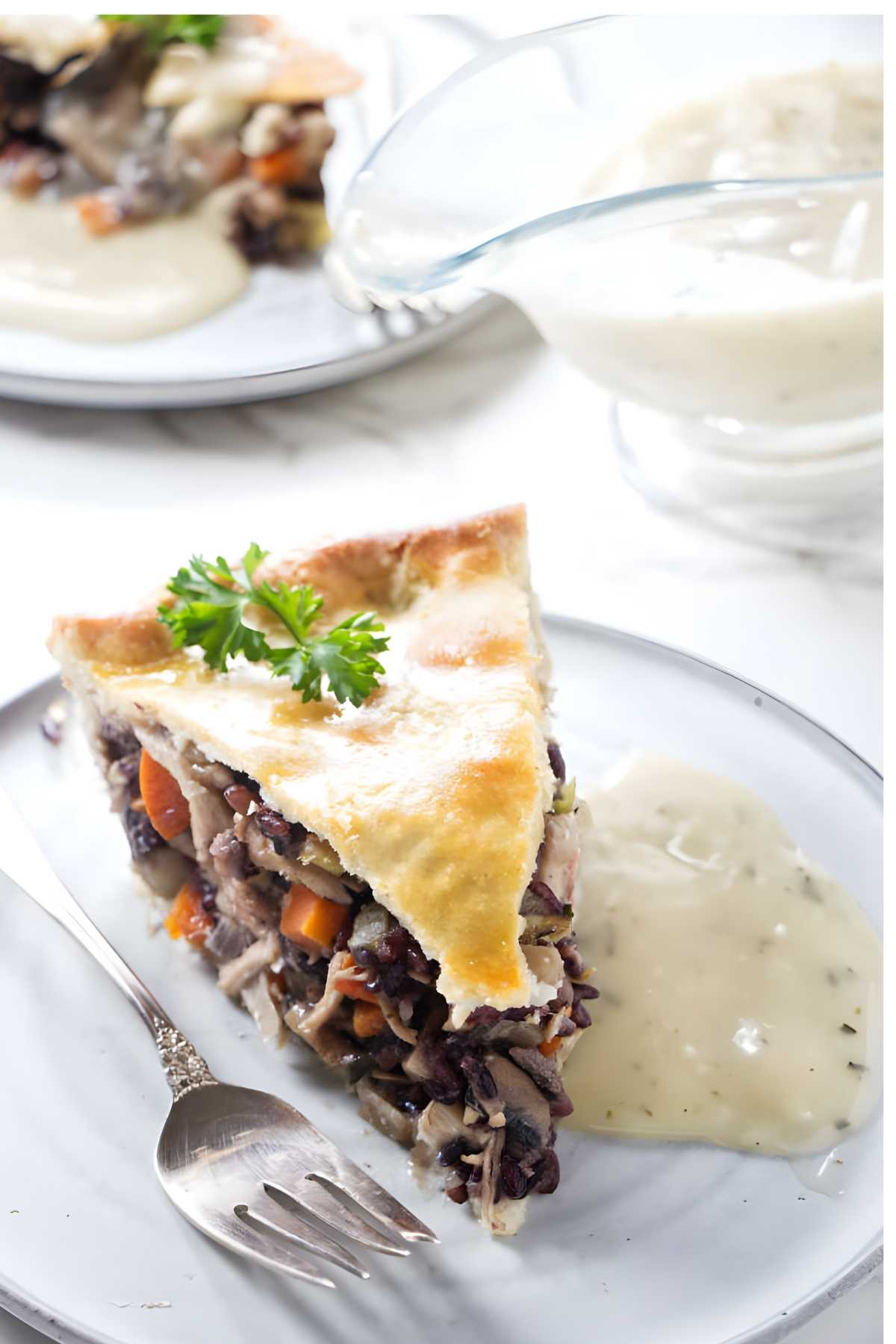 Chicken and rice pot pie slice with parsley and gravy on a white plate.