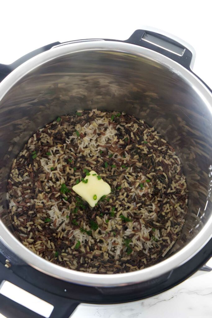 Cooked wild rice with butter and herbs in an Instant Pot, close-up.