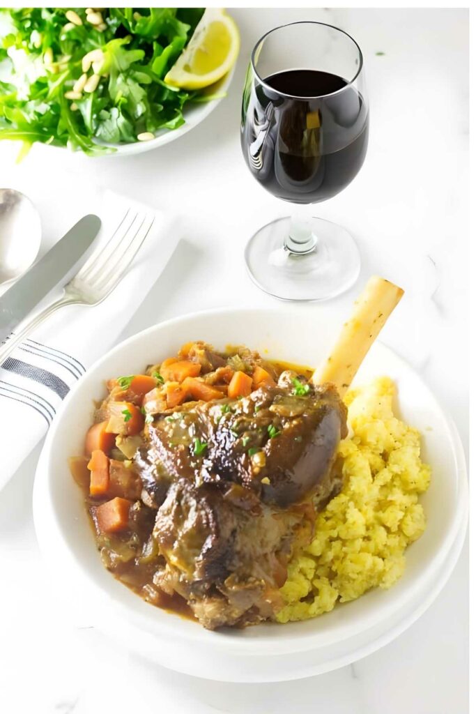 Braised lamb osso buco with carrots, and mashed potatoes with red wine on table.