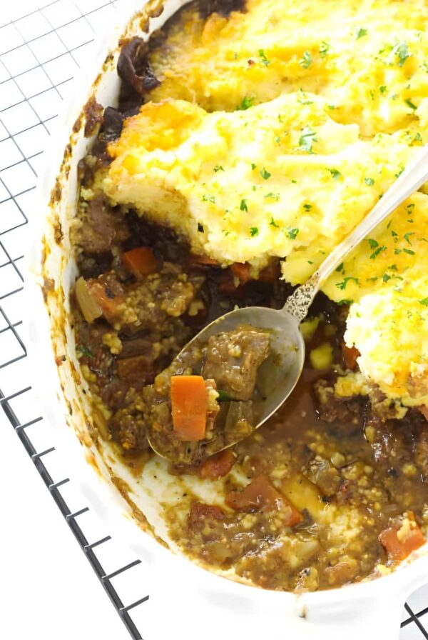 Close-up of lamb casserole, spoon scooping filling and mash.