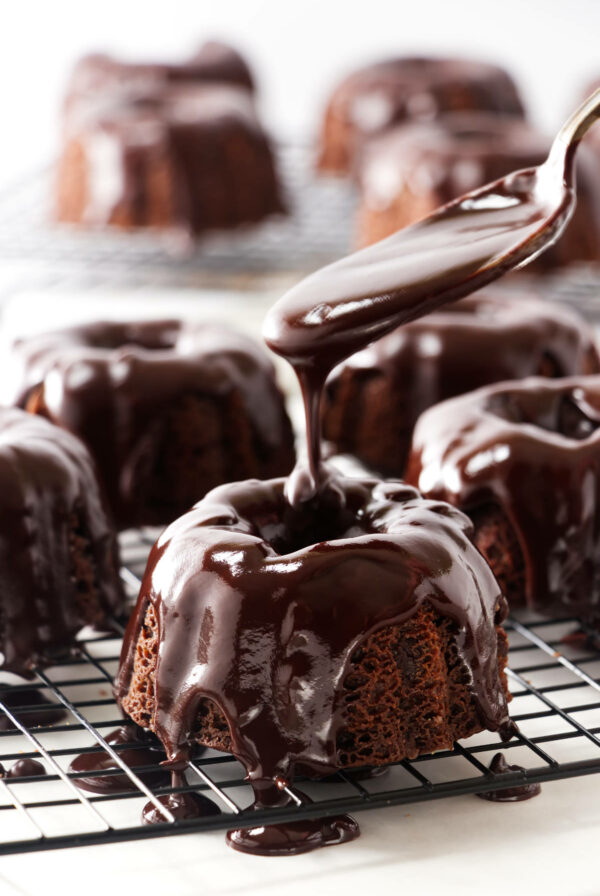 Drizzling chocolate glaze over a mini bundt chocolate cake.
