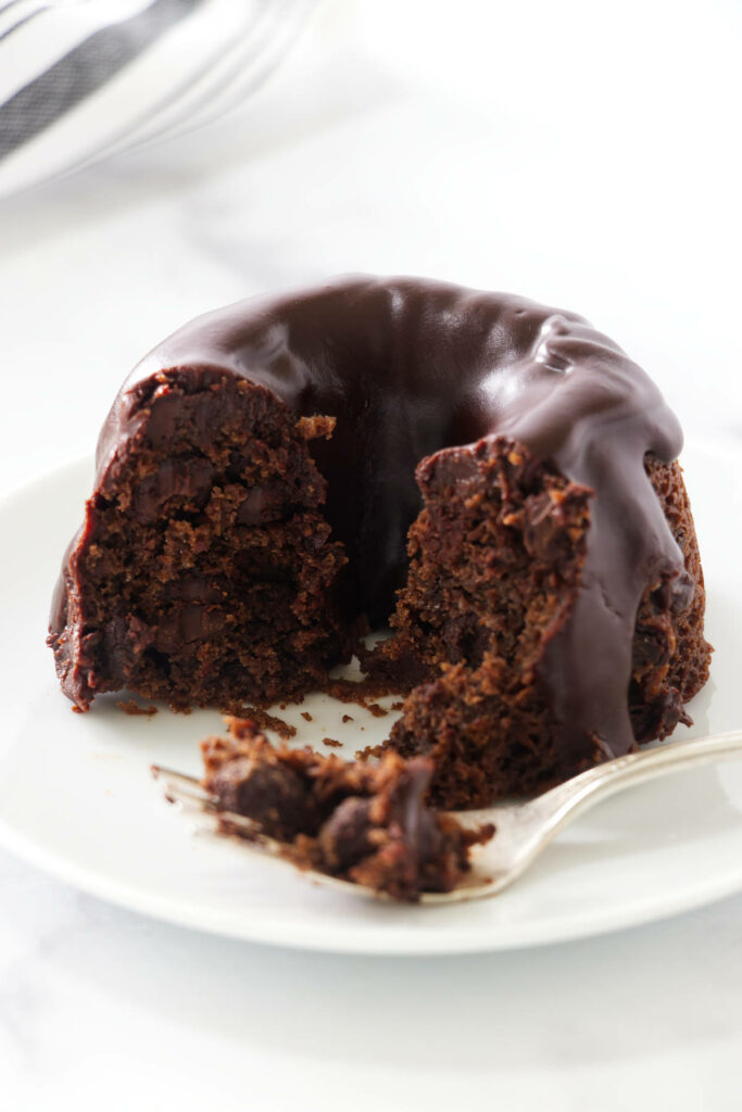 Chocolate bundt cake with glaze and a slice cut, fork holding a bite.