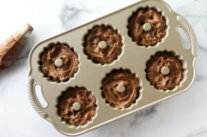 Placing chocolate cake batter into mini bundt cake pan.