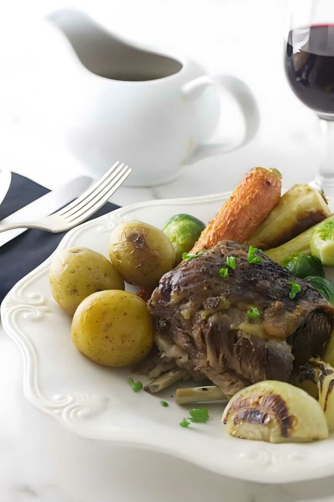 Pot roast with vegetables and herbs on a white plate.