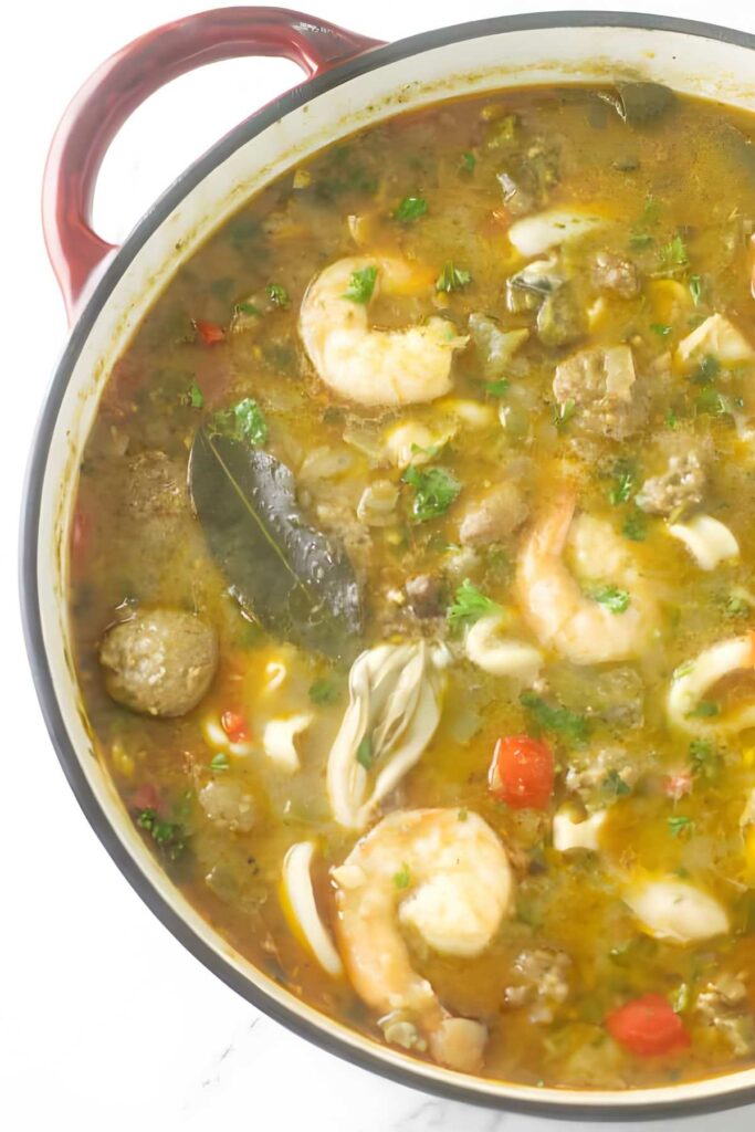 Seafood gumbo with shrimp, sausage, vegetables, and herbs in a pot.