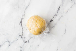 Wrapping pasta in plastic wrap to rest.