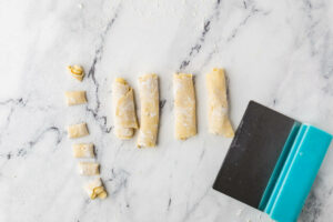 Slicing pasta dough into long pasta shapes.