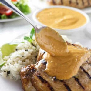 Grilled chicken with rice and salad, creamy sauce poured over the chicken.