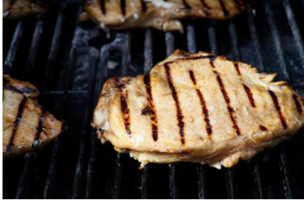 Close-up of grilled chicken breast with grill marks on a barbecue.
