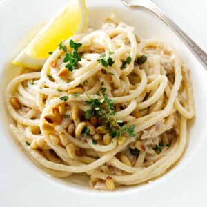 A bowl of tuna pasta garnished with lemon and herbs.