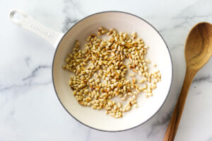 Toasting pine nuts in a skillet.