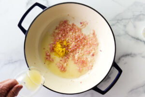 Adding lemon juice to the skillet with zest and shallots.