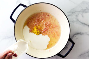 Adding cream to a skillet with the sauce.