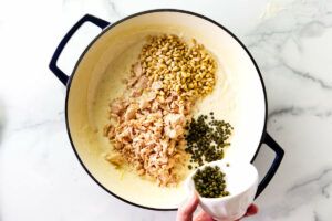 Adding capers and pine nuts to the tuna pasta sauce.