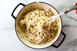 Mixing noodles with tuna and cream sauce.