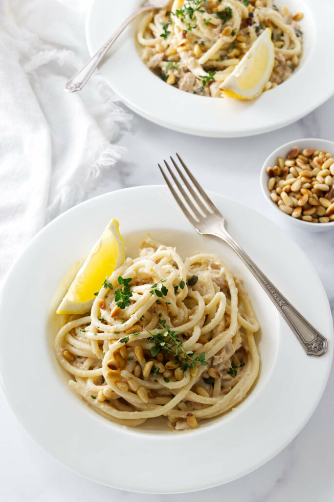 Noodles in a bowl mixed with tuna and lemon.