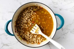 Adding white beans to the soup mixture.