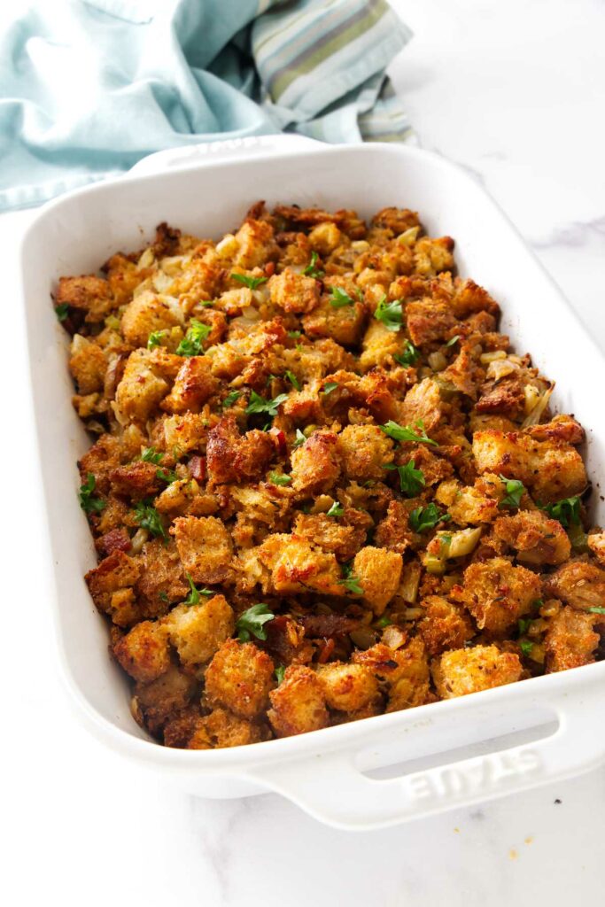 A casserole dish with filled with a fennel bread stuffing topped with parsley.