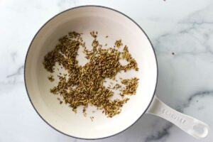 Toasting fennel seeds in a skillet.