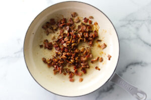 Browning bacon bits in a skillet.