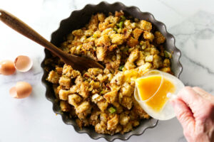 Pouring eggs into the stuffing mixture.